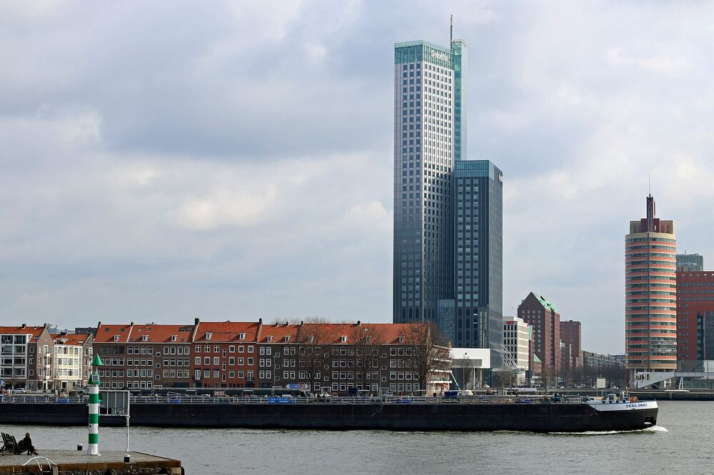De Rotterdamse skyline aan de Nieuwe Maas met een passerend schip